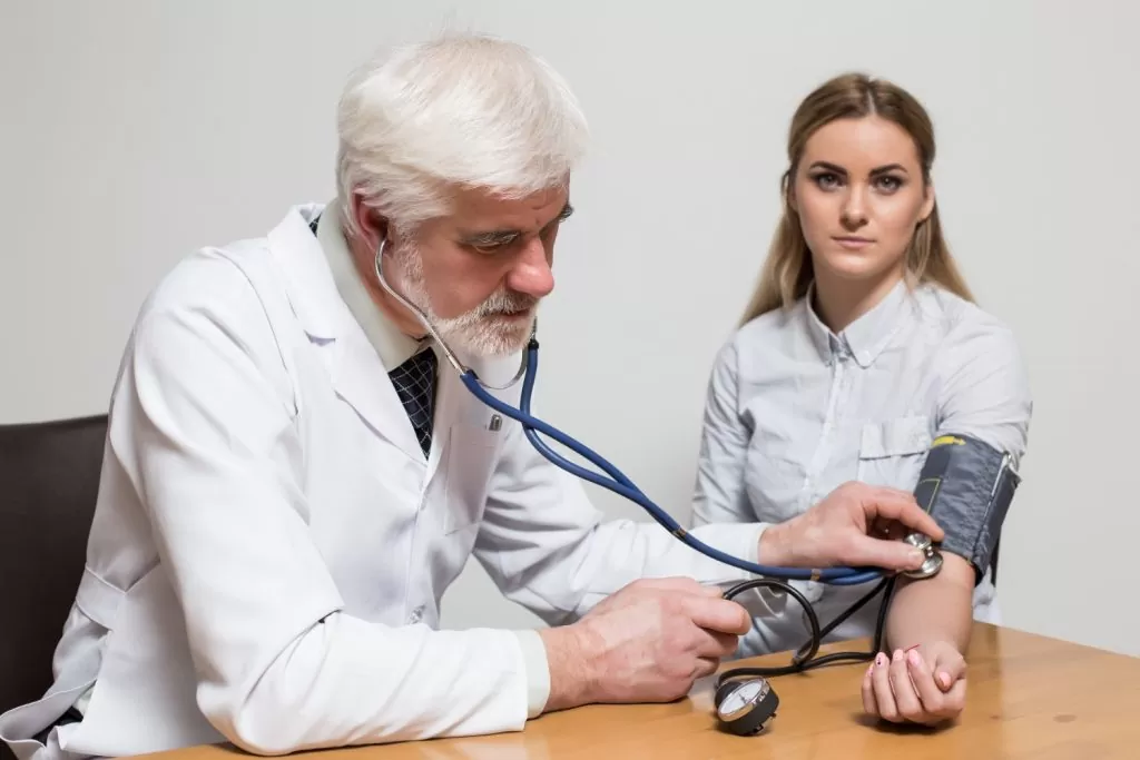 ação de indenização por doença adquirida no trabalho: médico medindo pressão de paciente